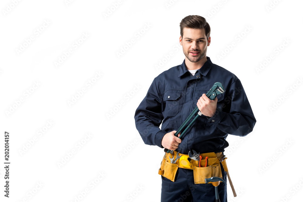 Smiling repairman wearing uniform with tool belt and holding wrench isolated on white Smiling repairman wearing uniform with tool belt and holding wrench isolated on white