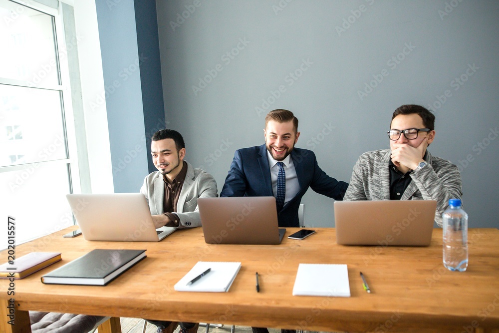 Three adult businesspeople sitting at desk with laptops in office Three adult businesspeople sitting at desk with laptops in office
