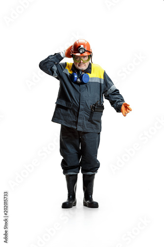 The studio shot of senior bearded male miner standing at the camera on a white background. © master1305
