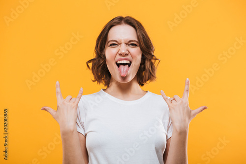 Emotional young woman showing rock gesture looking camera.