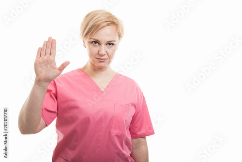 Attractive female nurse wearing pink scrubs taking oath gesture