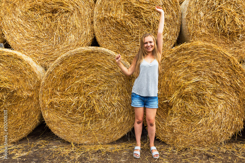 A smiling young woman with a blond with disheveled hair on the background of hay. Copy space. Nasty hair concept.