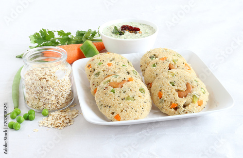 Oats Idli or cake, a healthy Indian vegetarian food, with vegetables like carrot, peas, green beans and capsicum, and cashew nuts, which is steam cooked.