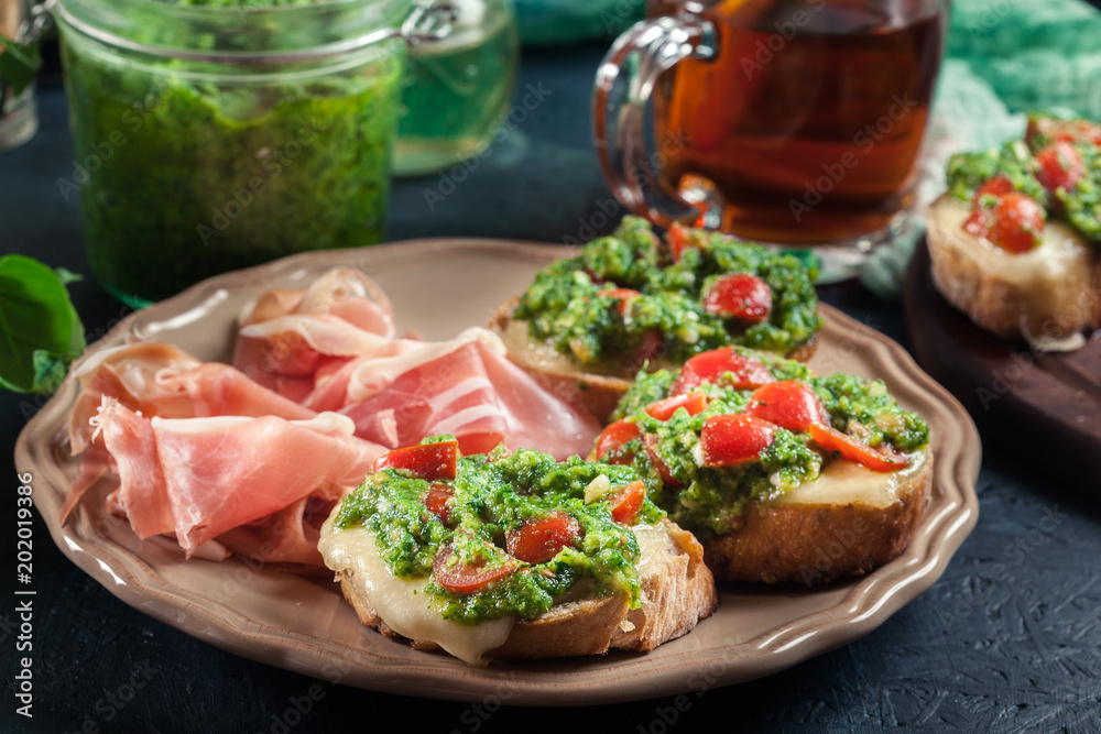 Bruschetta with fresh pesto, mozzarella and cherry tomatoes on a plate Bruschetta with fresh pesto, mozzarella and cherry tomatoes on a plate