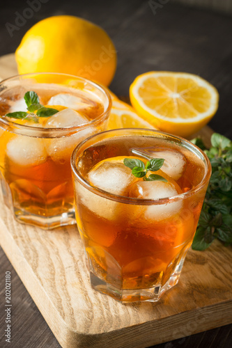 Glasses of cold ice tea with lemon, ice, mint on background. Homemade lemonade. Spring and summer drinks and beverages concept. 