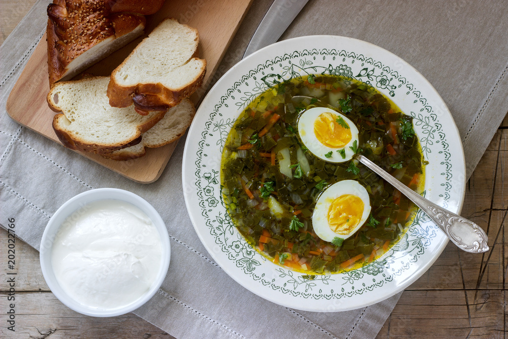 Vegetarian sorrel soup with egg, served with sour cream and bread. Rustic style. Vegetarian sorrel soup with egg, served with sour cream and bread. Rustic style.