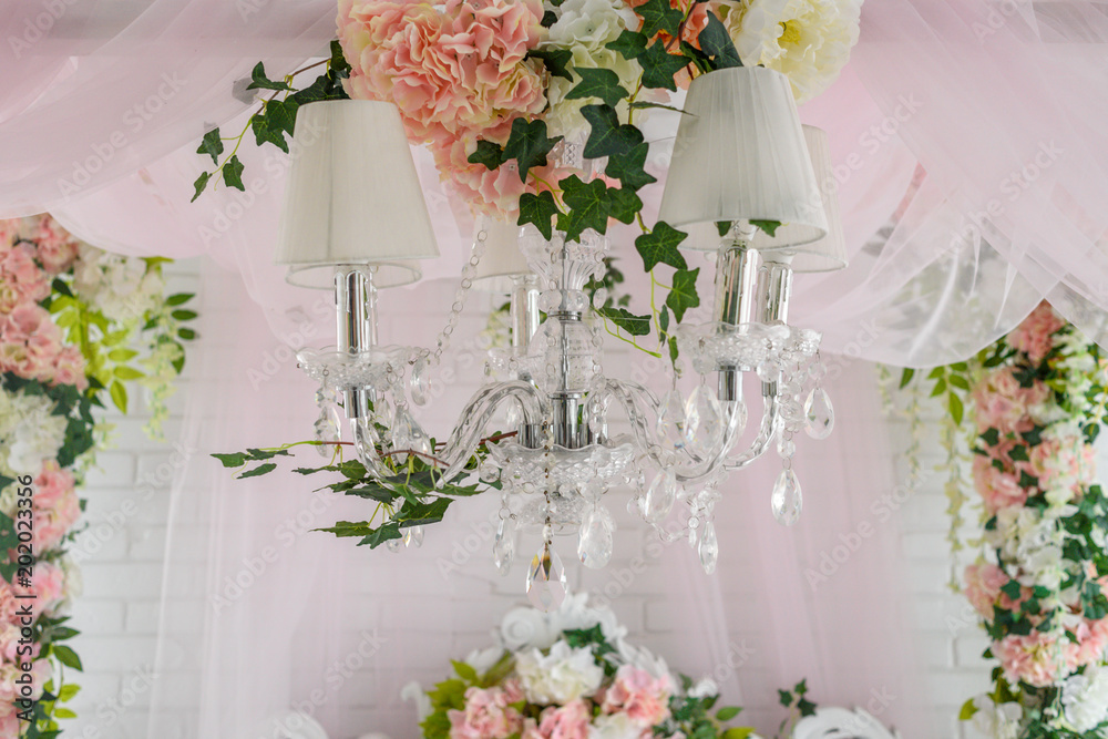 Φωτογραφία Close up of elegant crystal chandelier with white and pink flowers hanging above