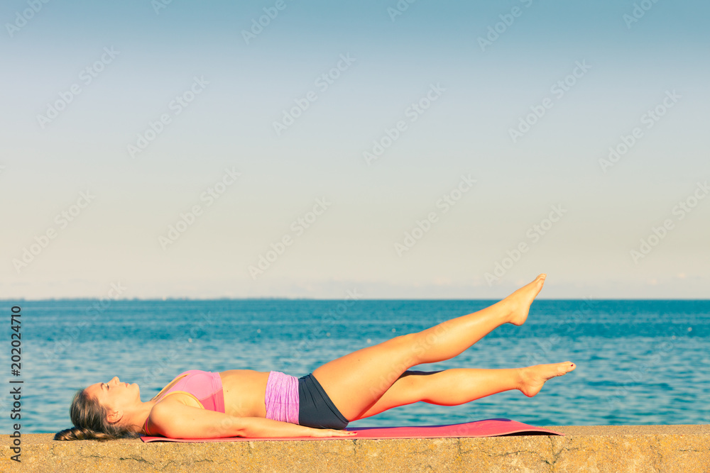 Woman doing sports exercises outdoors by seaside Woman doing sports exercises outdoors by seaside