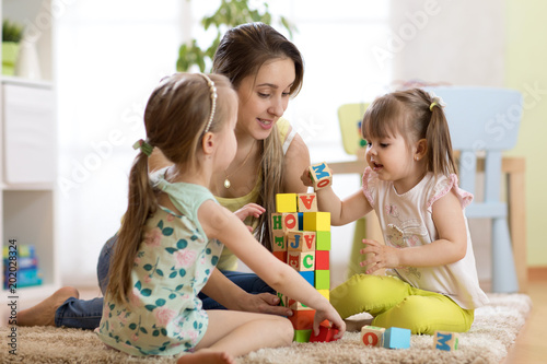 Children girls and mother playing together in nursery