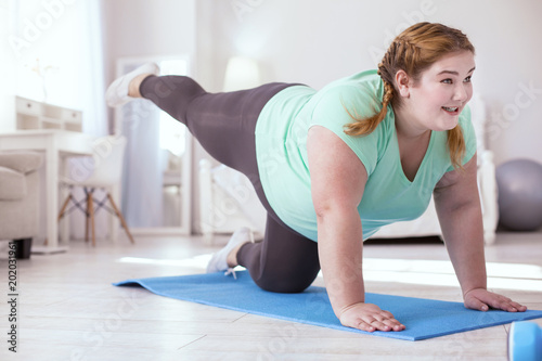 Last one. Obese young woman struggling with the last exercises while standing on all fours