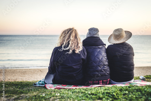 Three girls sitting on the blanket with the sea view