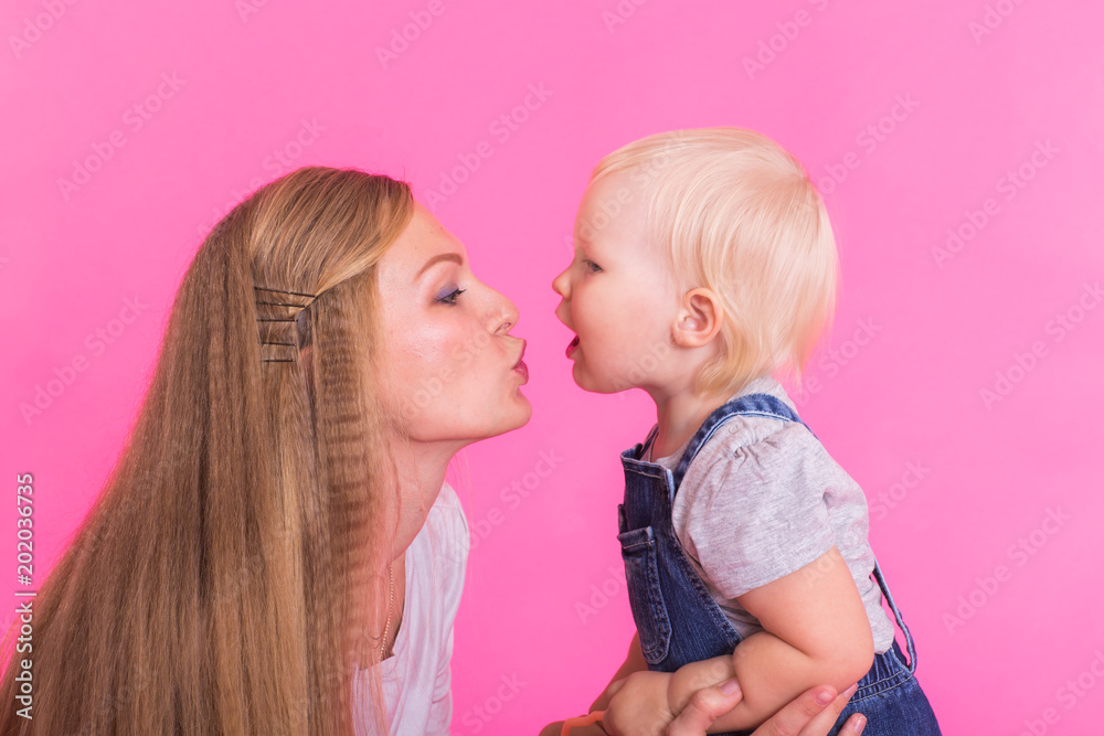 happy little girl and her mother having fun over pink background happy little girl and her mother having fun over pink background