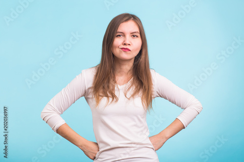 Pissed off angry grumpy young pessimistic woman with bad attitude thinking looking at you Negative human emotion face expression feeling reaction on blue background
