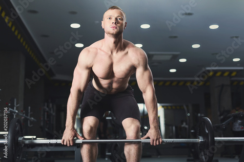 Muscular bodybuilder doing heavy deadlifts at gym