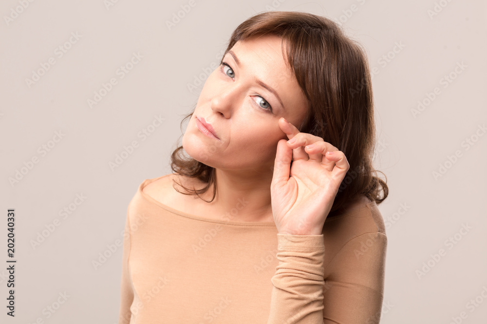 Attractive woman in light beige blouse lightly touching her eyelashes. Sloped head. Beauty concept. Mid age woman over 35 years old beauty concept. Attractive woman in light beige blouse lightly touching her eyelashes. Sloped head. Beauty concept. Mid age woman over 35 years old beauty concept.