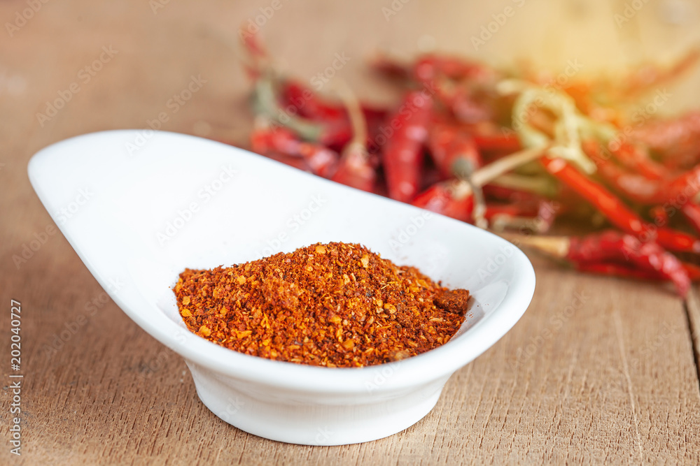 Cayenne pepper in white dish and dried chilli on wood table. Cayenne pepper in white dish and dried chilli on wood table.