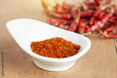Cayenne pepper in white dish and dried chilli on wood table.