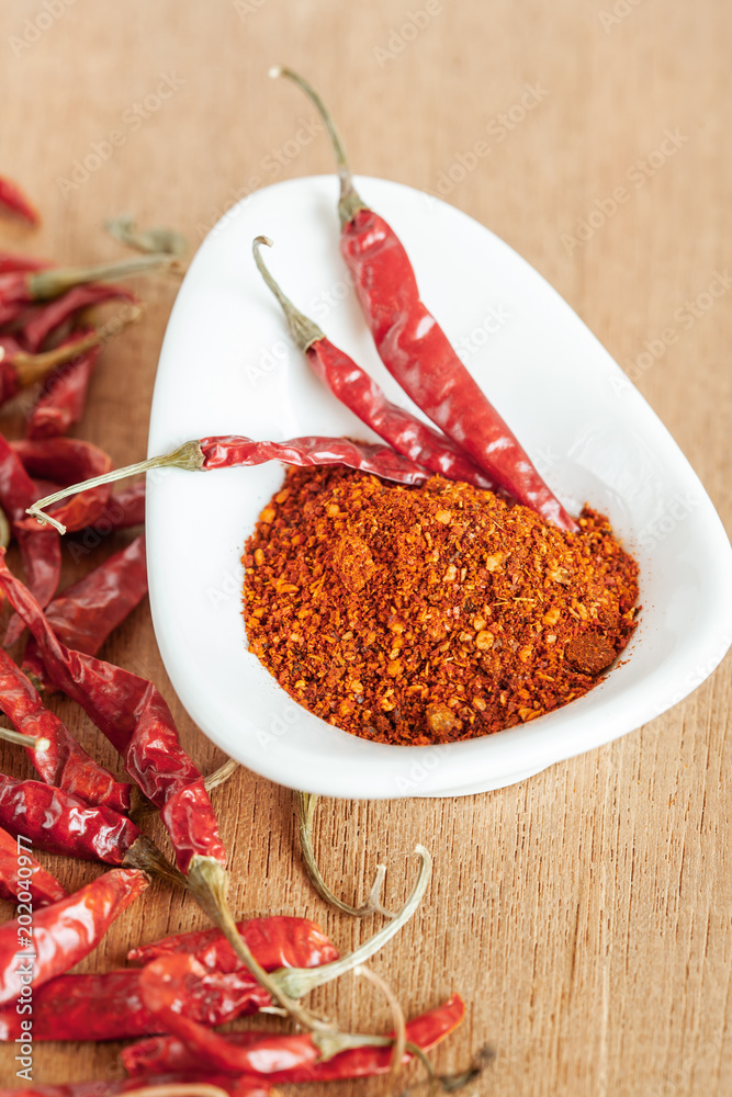 Cayenne pepper in white dish and dried chilli on wood table. Cayenne pepper in white dish and dried chilli on wood table.