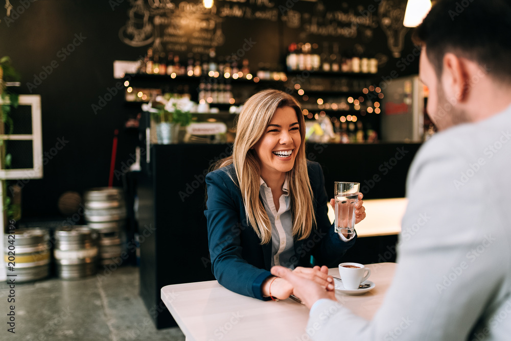 Laughing woman and man holding hands while enjoy coffee