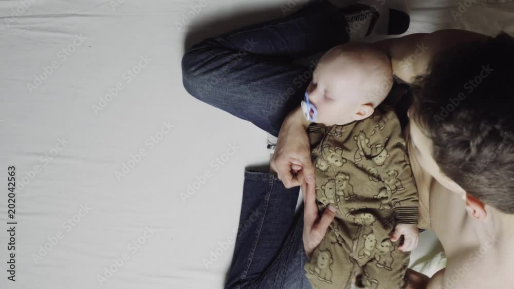 The baby sleeps in the arms of his father. 4k. Top view The baby sleeps in the arms of his father. 4k. Top view