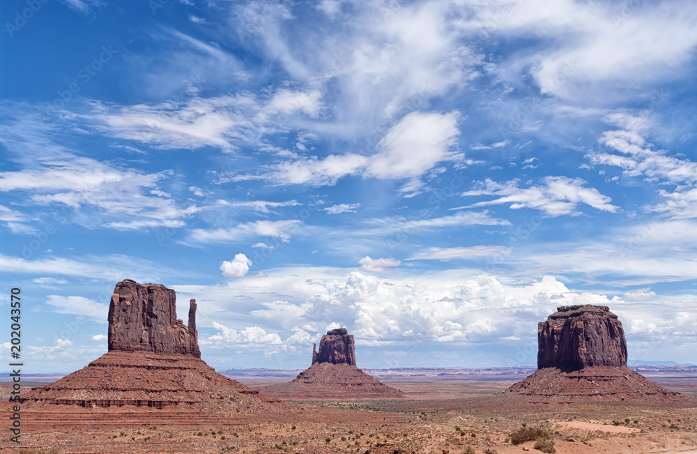 View of the famous Monument Valley, Colorado, USA, in daylight with blue sky full of clouds View of the famous Monument Valley, Colorado, USA, in daylight with blue sky full of clouds