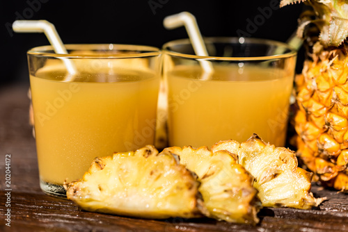 Pineapple juice and slice placed on a wooden table photo