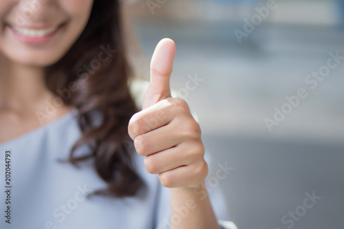 successful girl pointing thumb up; portrait of cheerful smiling woman pointing up approving, yes, ok, good, thumb up gesture; asian woman young adult model