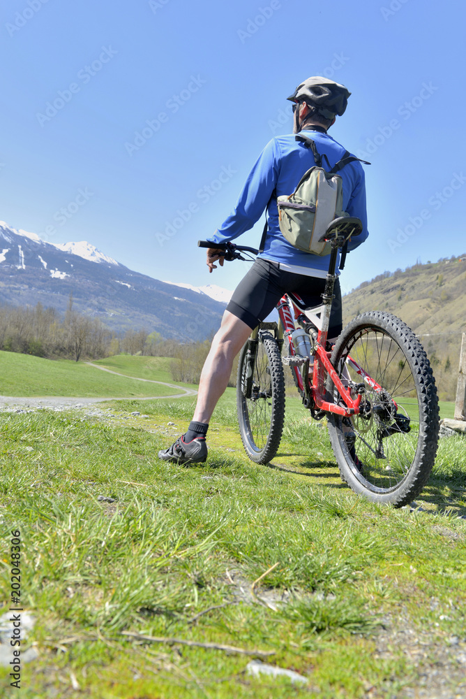 Cyclist in mountain bike near a path looking at the mountain far off