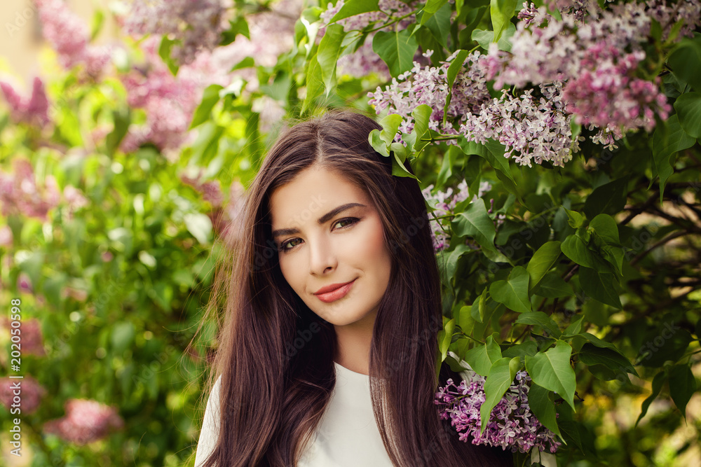 Pretty brunette woman with long healthy hair and natural makeup on floral background outdoors Pretty brunette woman with long healthy hair and natural makeup on floral background outdoors