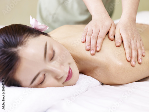young asian woman receiving massage in spa salon, focus on the masseuse's hands