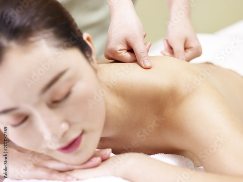 beautiful young asian woman receiving massage in spa salon, focus on the hands