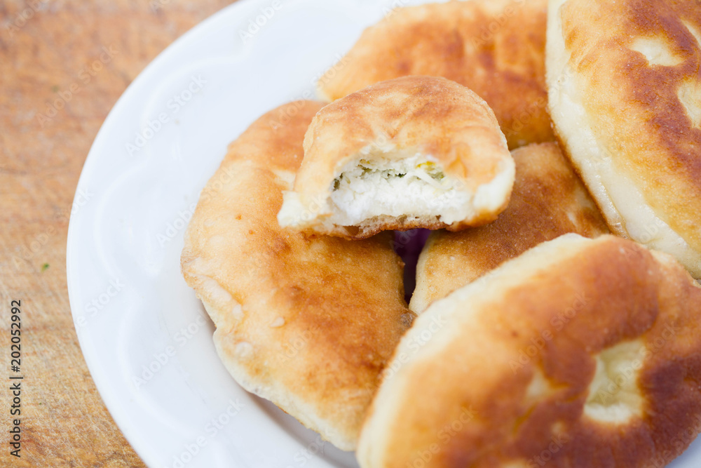 Fresh baked pastries filled with vegetables and cheese on wooden backgroun