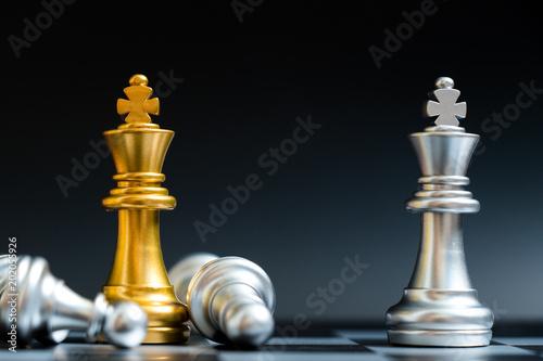Gold and silver king chess piece face in chessboard on black background