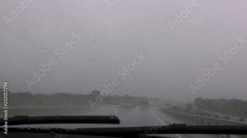 Driving in rainy weather. View of countryside in the rainy weather in the spring. Front view through car window.
