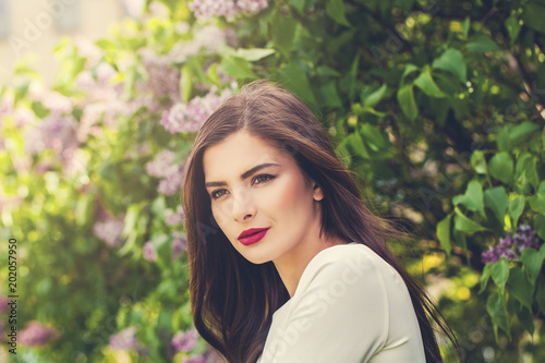 Beautiful female model woman in flowers garden outdoors, portrait