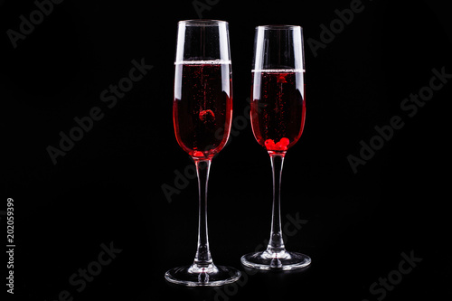 Glass with berries and red champagne alcohol cocktail stands on black background