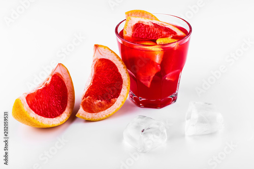 Blood orange gin and tonic cocktail served with slices of orange and ice in a glass on white background photo