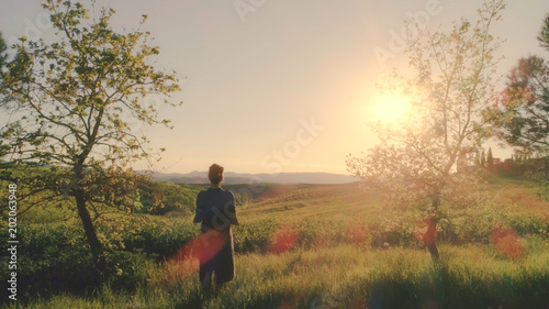 Young woman looking at sunset over Tuscany hills