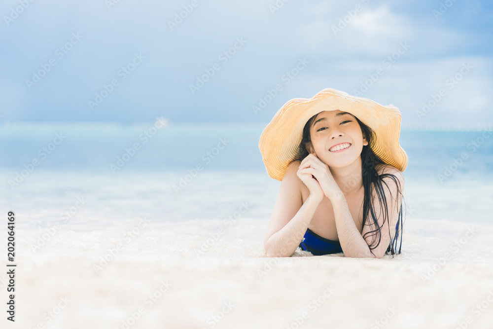 Pretty beautiful asian woman wearing colourful swimwear bikini with hat living sunbathing on the beach in the summer Pretty beautiful asian woman wearing colourful swimwear bikini with hat living sunbathing on the beach in the summer