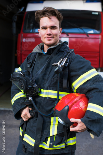 Portrait of a young fireman on the background of a fire truck