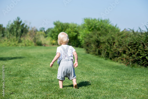 little boy runs along the green grass. © Alex