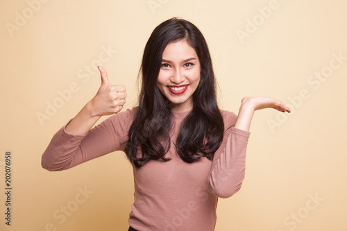 Beautiful young Asian woman show palm hand and thumbs up.
