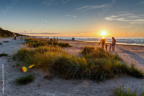 Warm summer sunset. Beach landscape with silhouettes of people on the background. Jurmala resort, Latvia, Baltic Sea. Vacation concept 