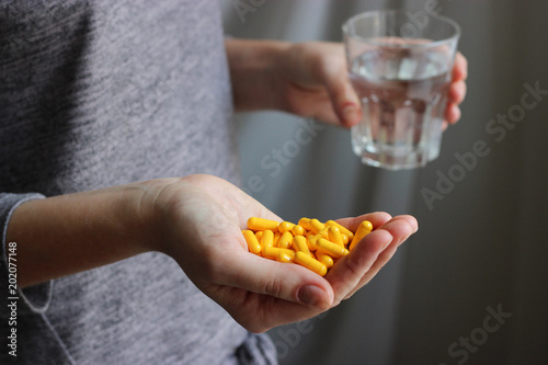 a handful of pills and a glass of water in female hands. Concept of health.