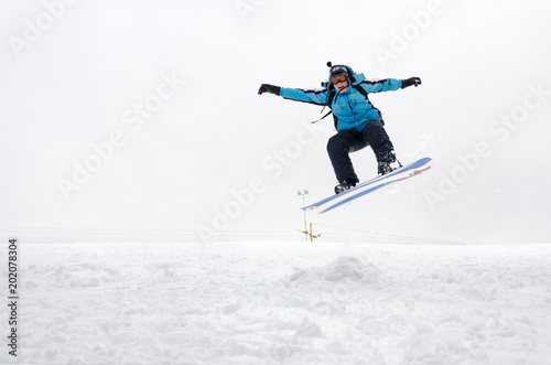 Snowboarder making jump high in gray sky