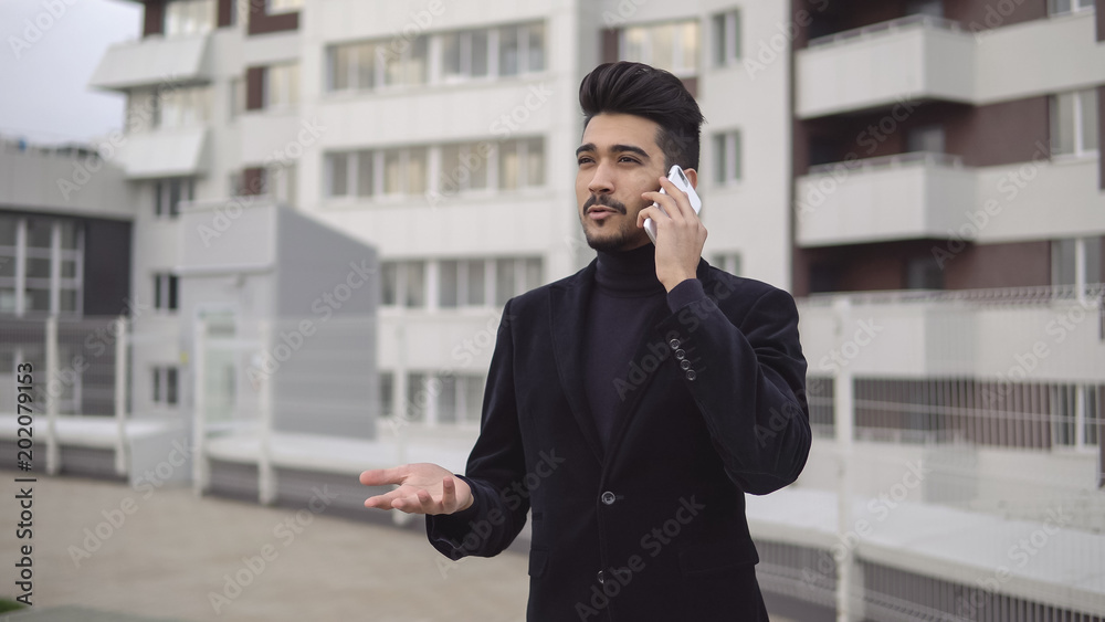 Happy stylish businessman hear good news on the phone and rejoices with happy emotions outdoors near office building Happy stylish businessman hear good news on the phone and rejoices with happy emotions outdoors near office building