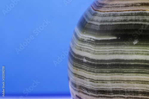 Fototapeta Naklejka Na Ścianę i Meble -  Macro photo texture of polished onyx stone on a blue background. Photo for the site about geology, stones, jewelry, handwork, textures,art, astronomy.