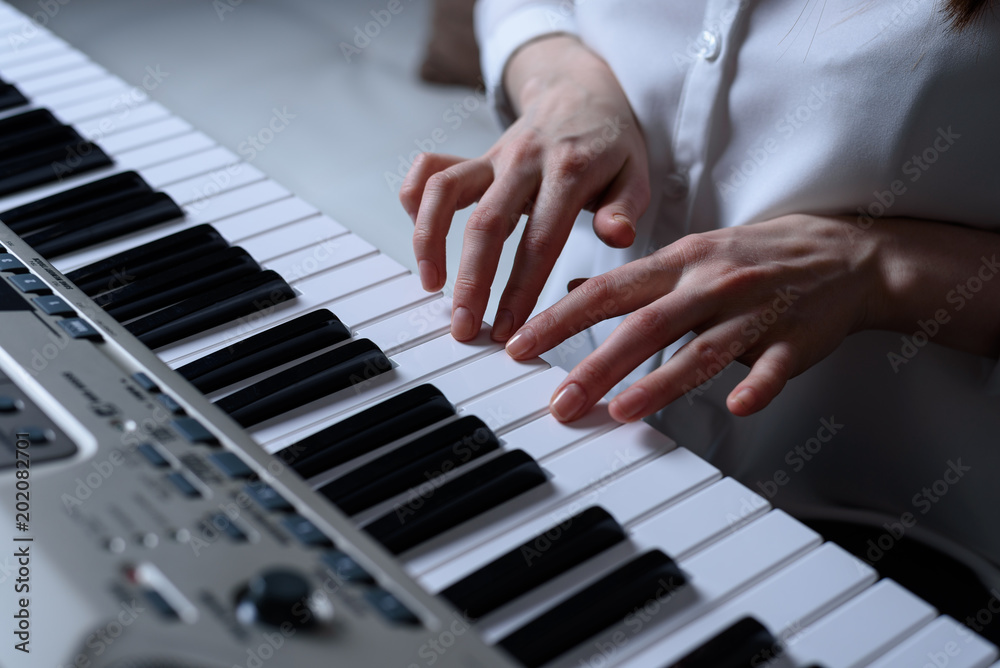 Front view of female hands practiced playing the synthesizer