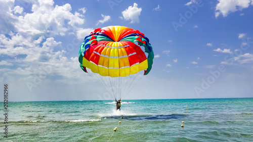 Happy couple Parasailing on beach in summer. Couple under parachute take off hanging mid air. Having fun. Tropical Paradise. Positive human emotions, feelings, family, children, travel, vacation