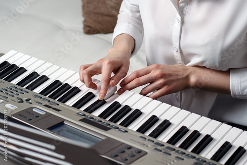 large image of female hands playing the synthesizer